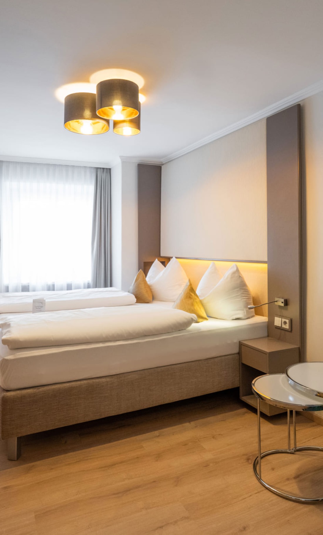 Beige Kissen und Lampe vor braunen Vorh&auml;ngen