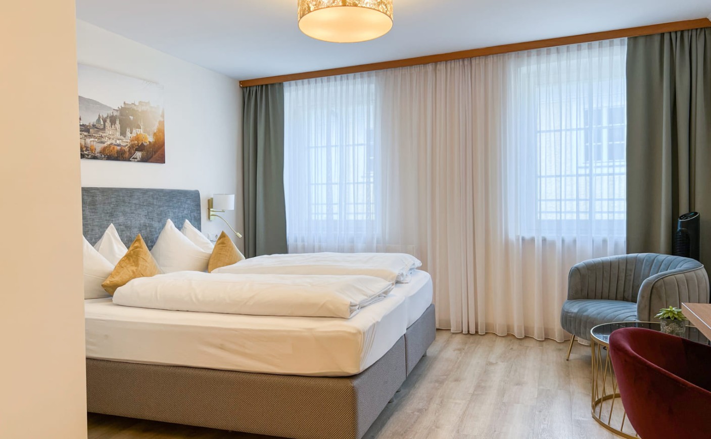Dreibettzimmer in der Trumer Stube Salzburg mit komfortablem Doppelbett und Sitzecke