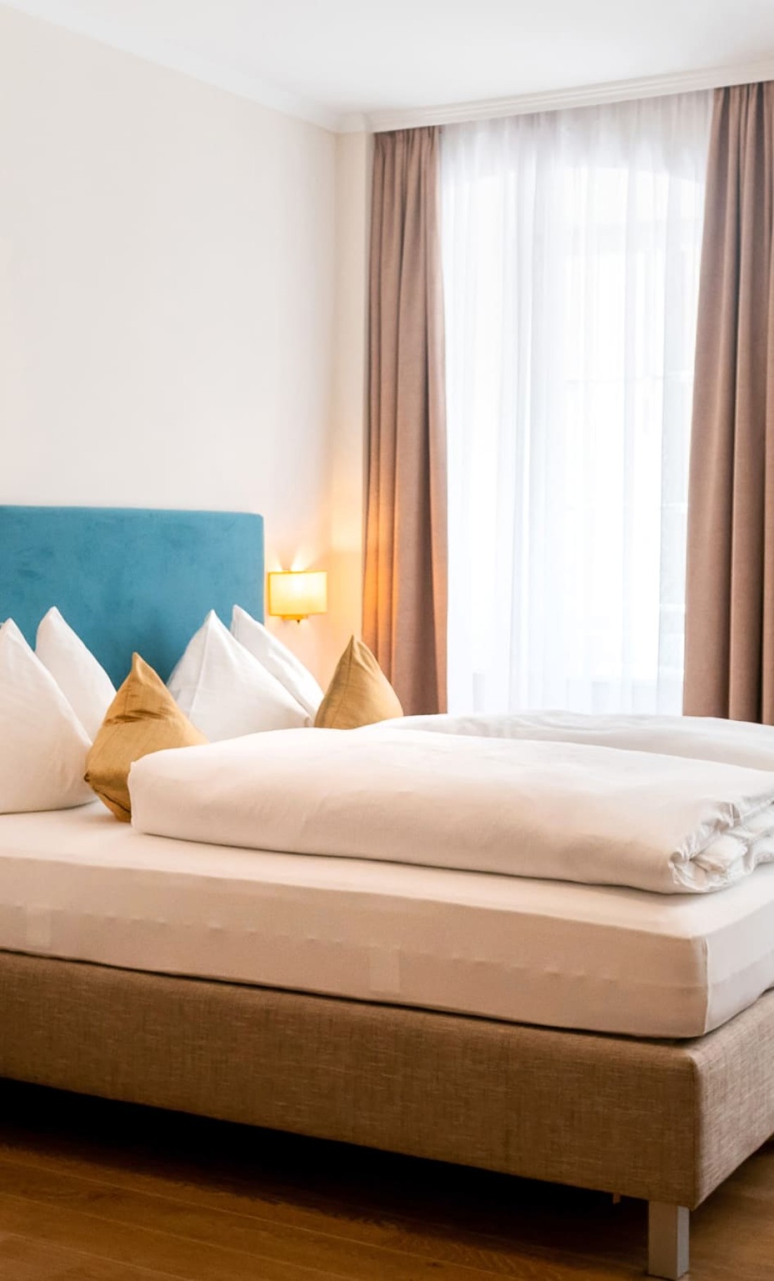 Gem&uuml;tliches Doppelbett mit stilvollen Kissen und viel Tageslicht im Dreibettzimmer