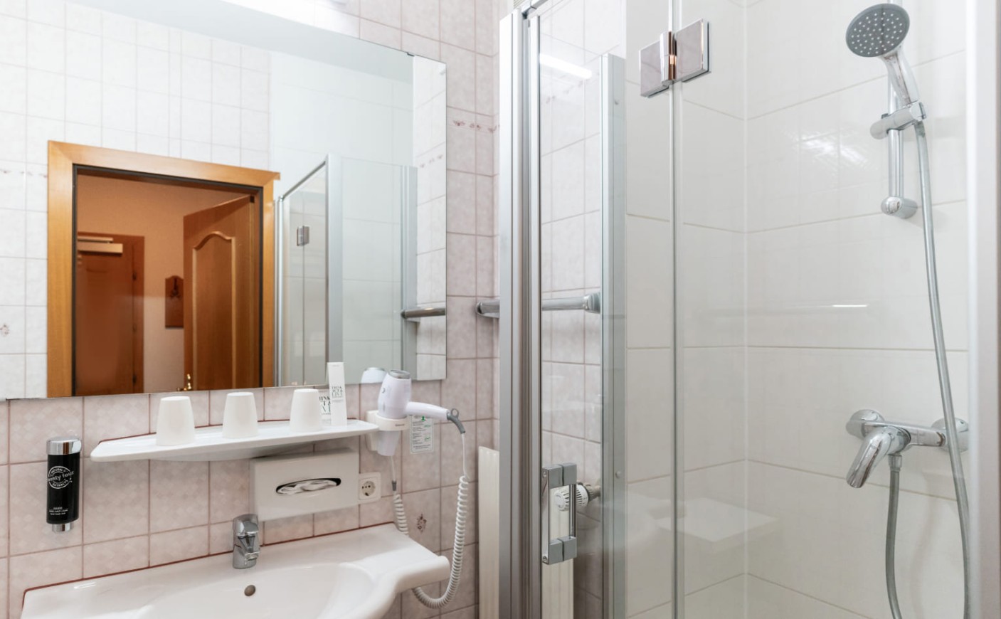 Badezimmer mit Dusche und Waschtisch im Dreibettzimmer