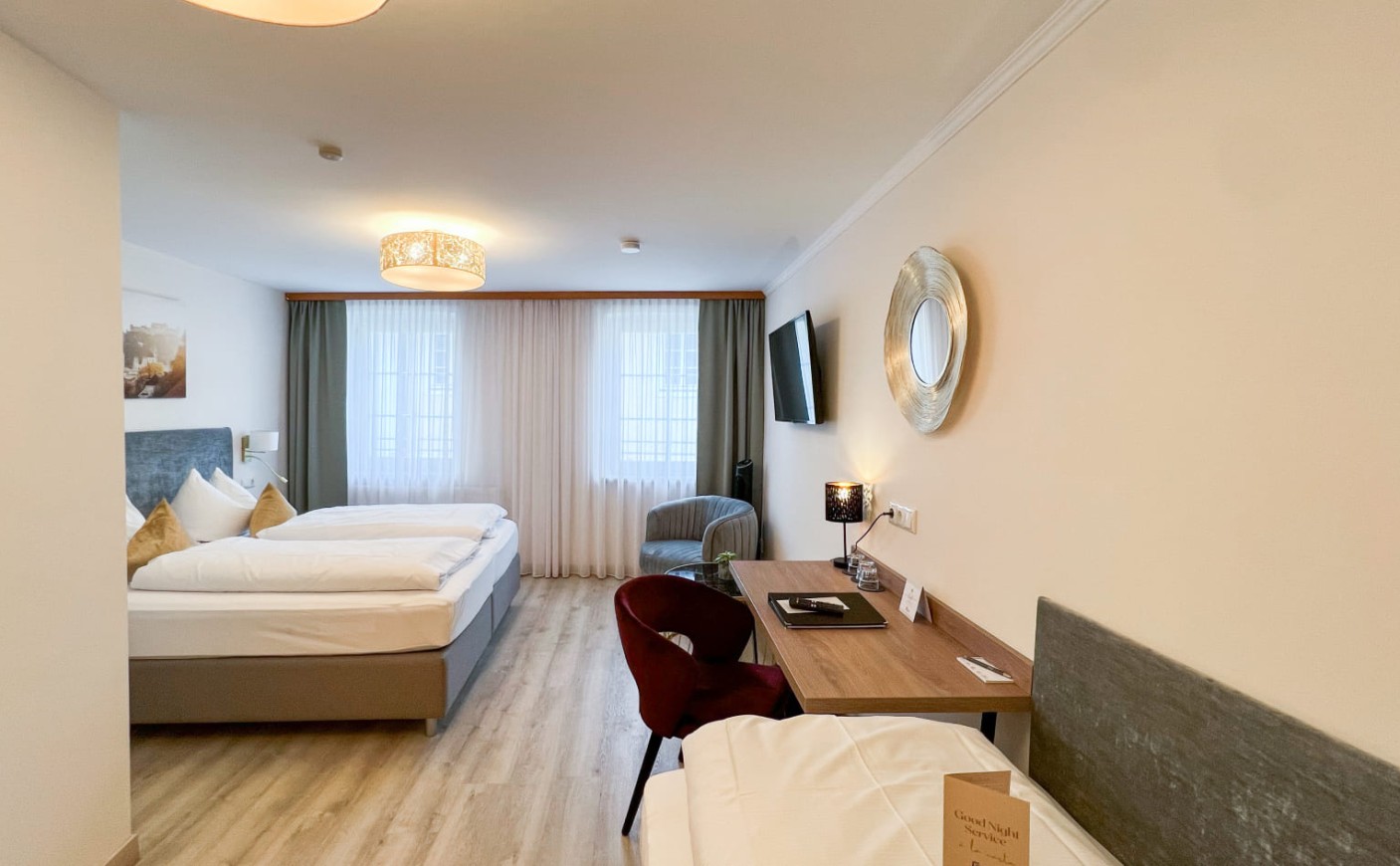 Dreibettzimmer in der Trumer Stube Salzburg mit Schreibtisch und viel Tageslicht