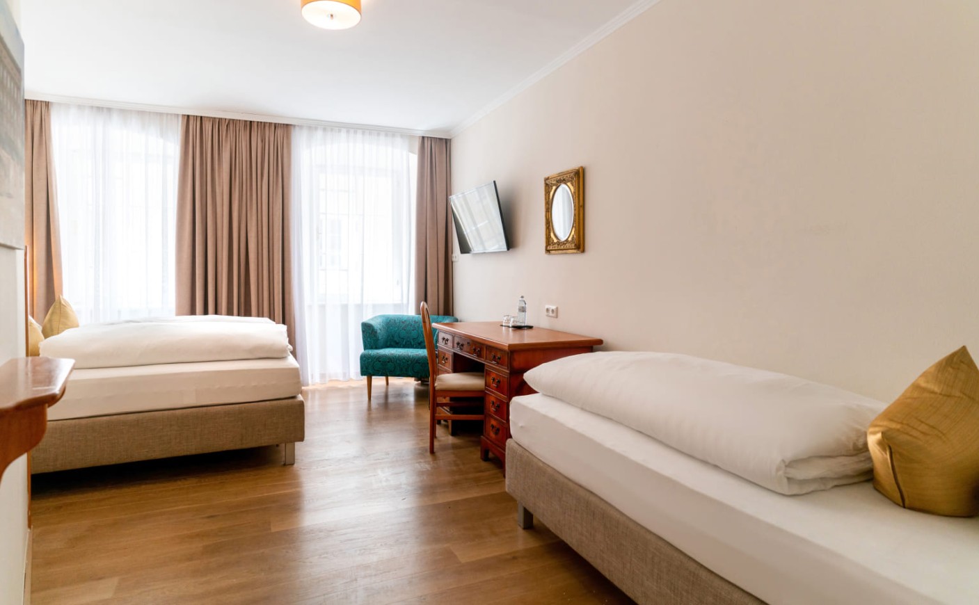 Dreibettzimmer mit Einzelbett, Schreibtisch und wohnlichem Flair in der Salzburger Altstadt